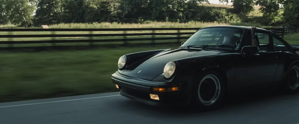 Porsche 911 negro en una carretera rural, de las imágenes de prensa de Porsche Design para el Chronograph 1 Utility